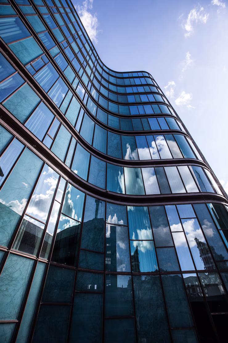 high-rise-building-glass-facade-with-reflection-surrounding-buildings_181624-6364.avif